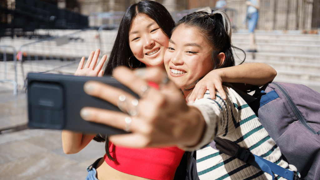 two happy young asian women taking vacation selfie