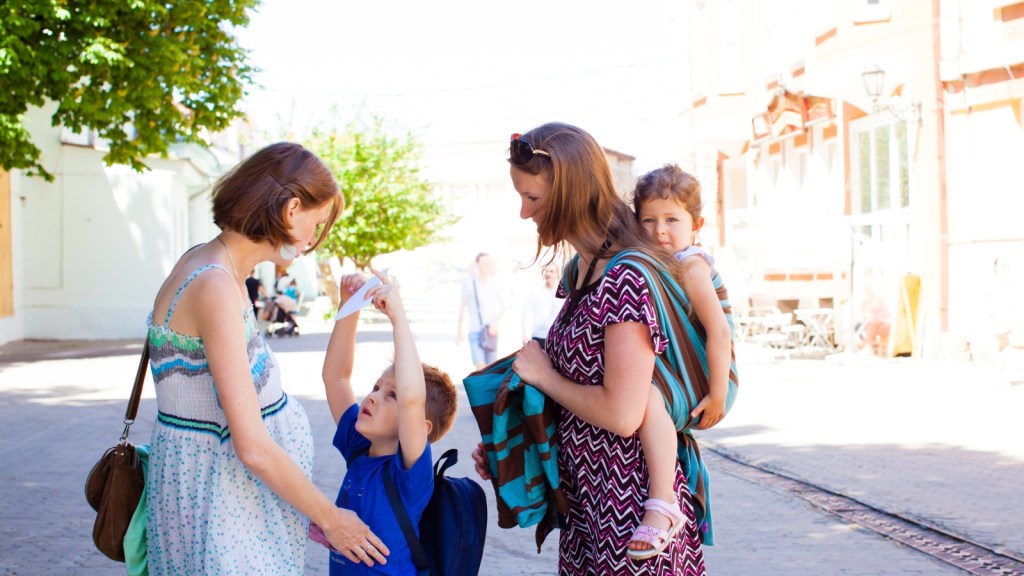 two women talking with kids running around