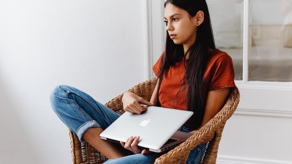 upset woman holding computer looking out window