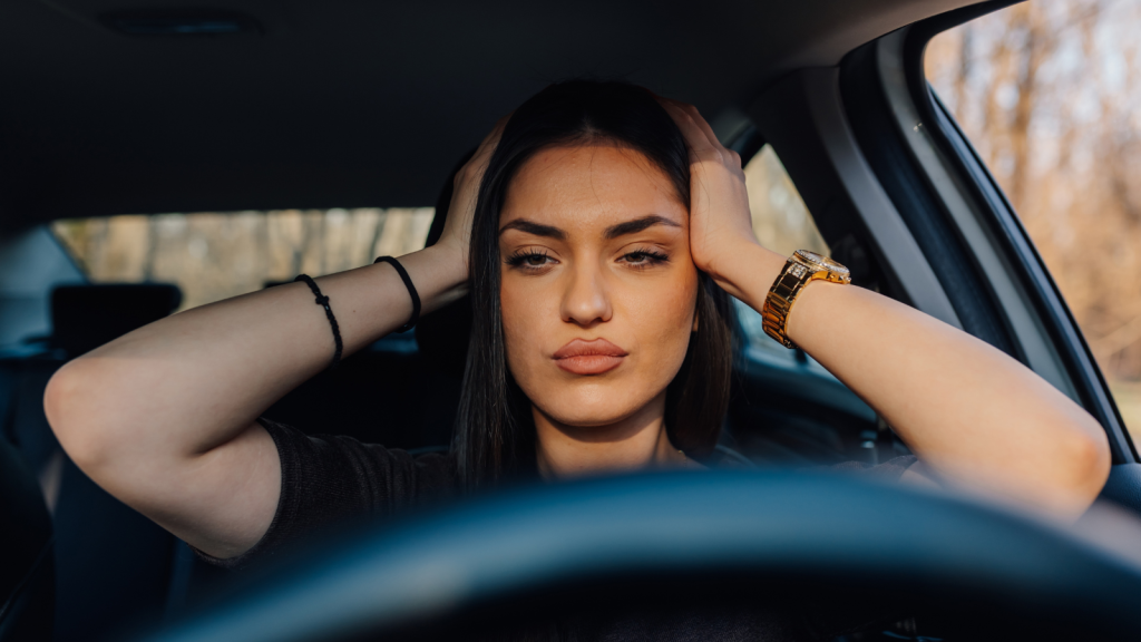 woman gripping her head frustrated in the car