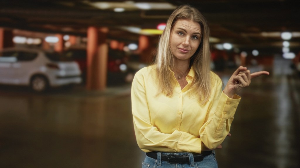 woman pointing to neighbors car in parking garage