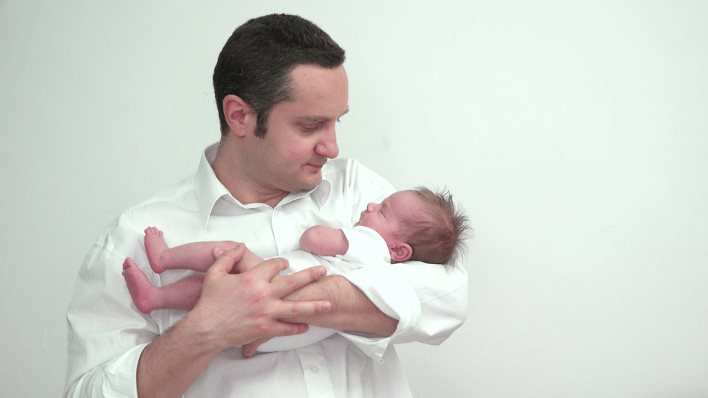 young father standing and holding newborn baby