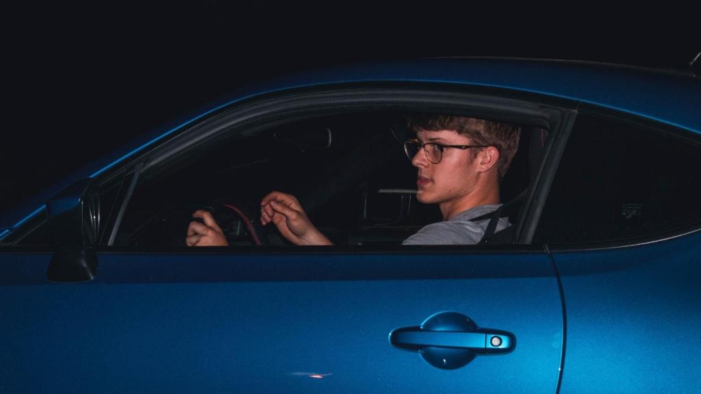 young man driving blue car