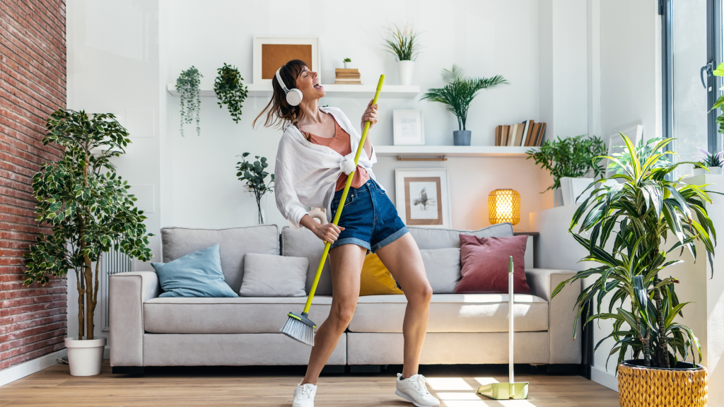 young woman dancing while cleaning the house