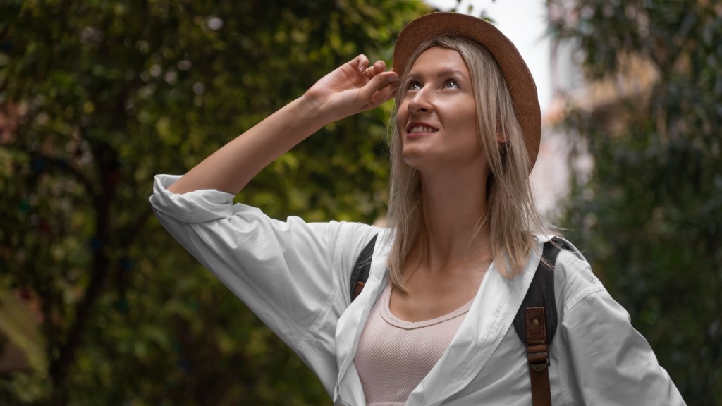 What Was Supposed To Be A Romantic City Visit Turned Into An Argument When Her Boyfriend Asked Her To Spend The Trip Babysitting His Niece young woman on vacation with hand on hat