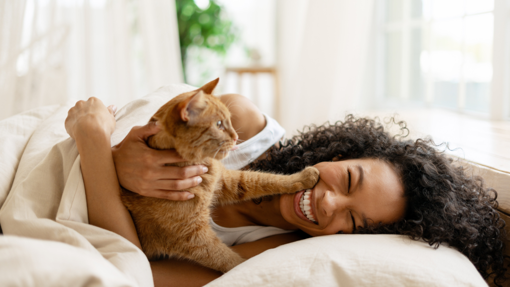young woman smiling and playing with her cat