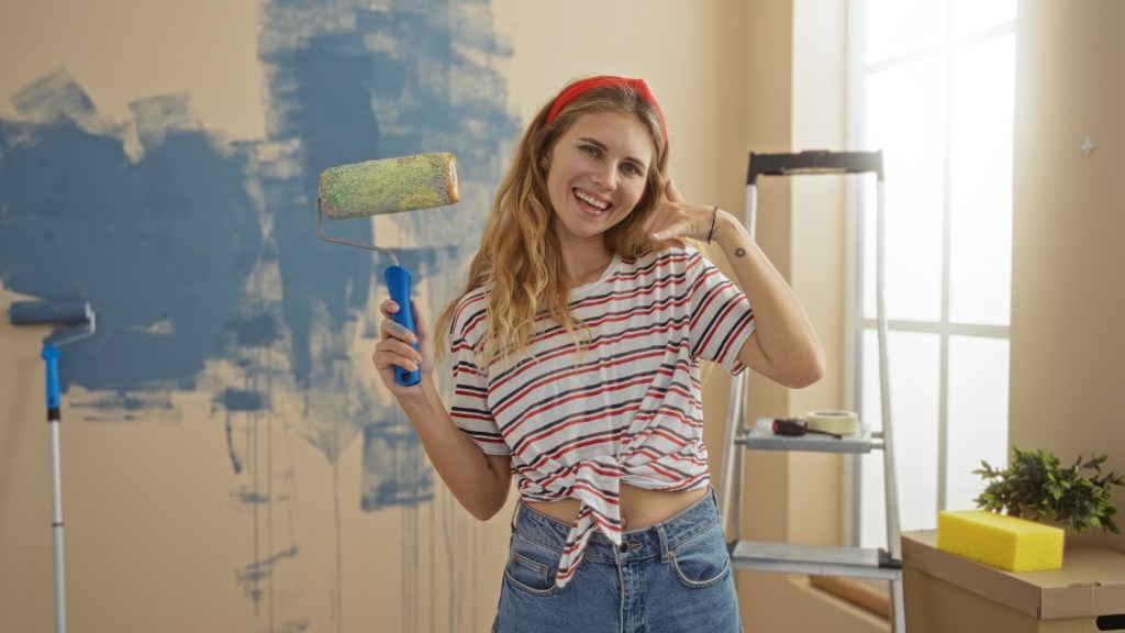 young woman smiling painting apartment