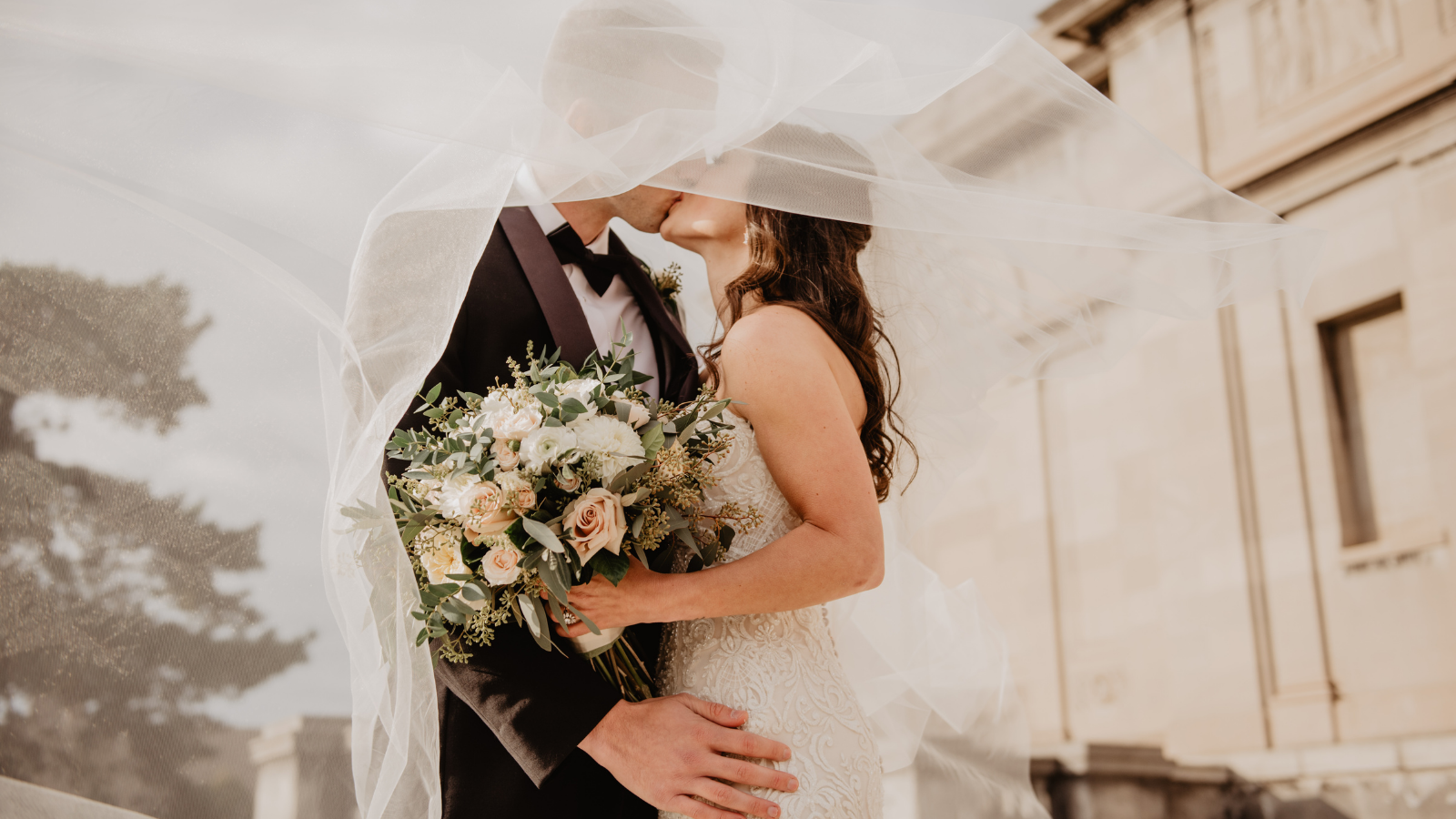 A couple kissing under their veil on their wedding day