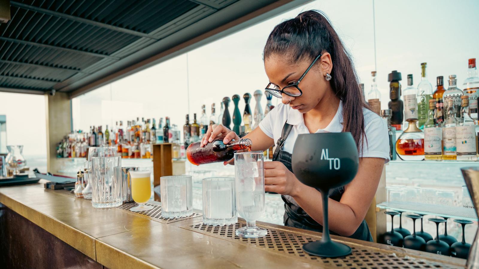 Two Former Baristas Started Working At The Same Bar, But Their New Jobs Started Putting Their Friendship At Risk A woman pouring drinks behind a bar