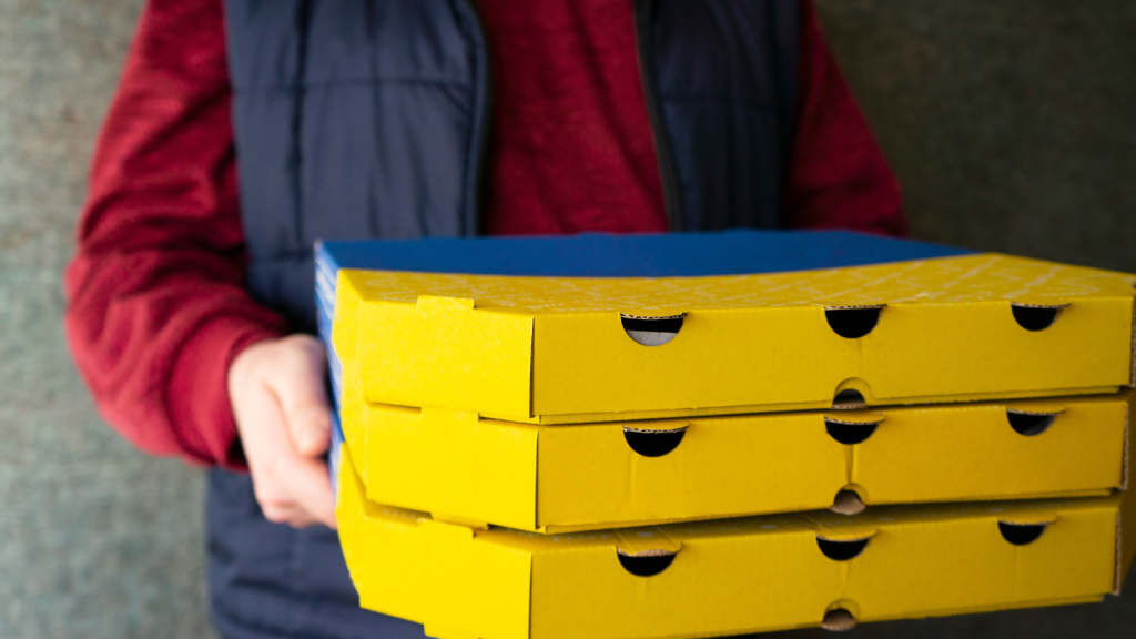 Employee handing several boxes of pizza