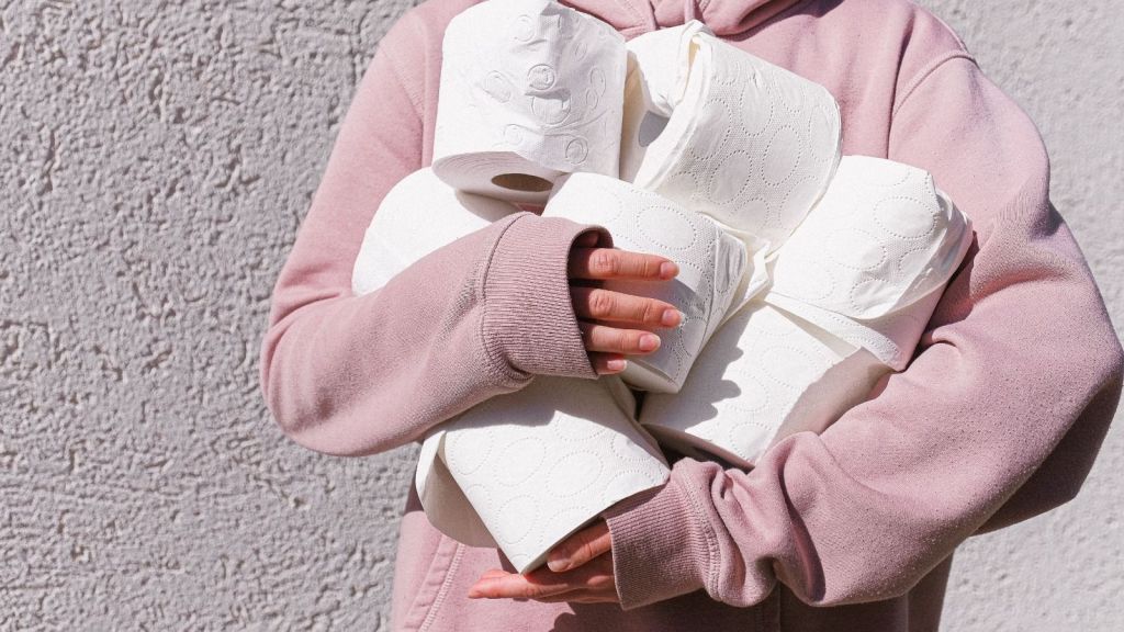 Woman cradling many rolls of toilet paper