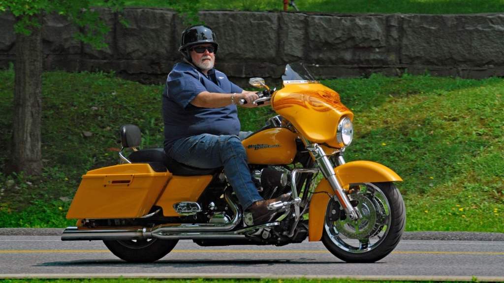 Man riding an orange Harley Davidson