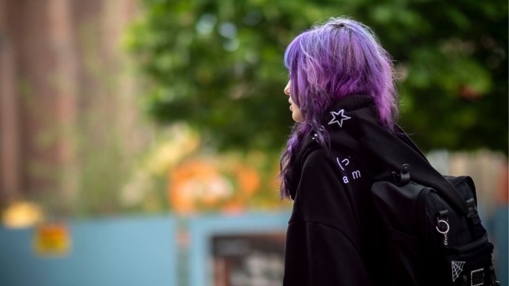 Teen girl with purple hair walking outside