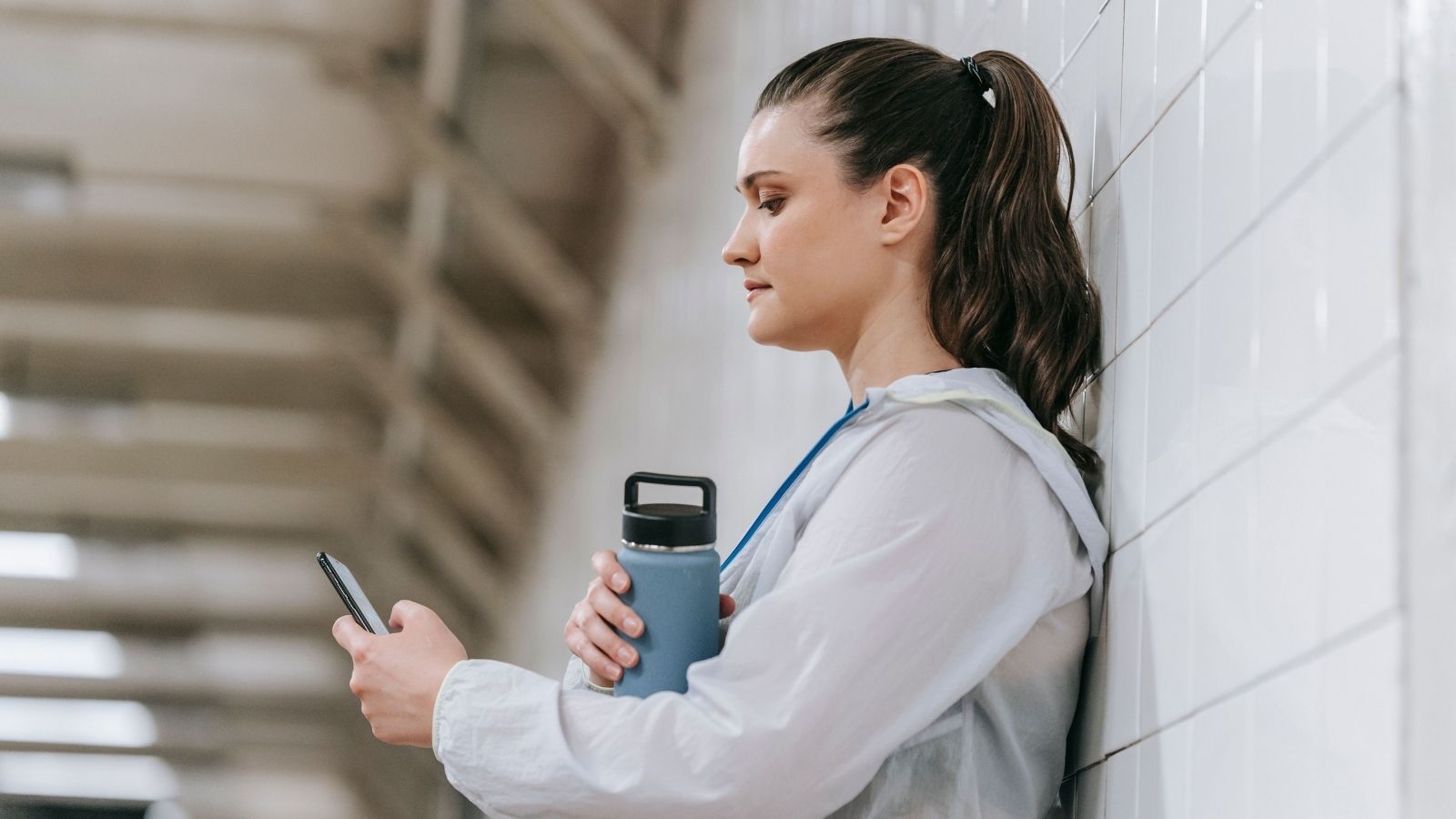 She Maintained a Water Bottle at Her Station After Dehydration—Then a Coworker Reported Her for a Policy Infraction Woman stressed and leaning against a wall