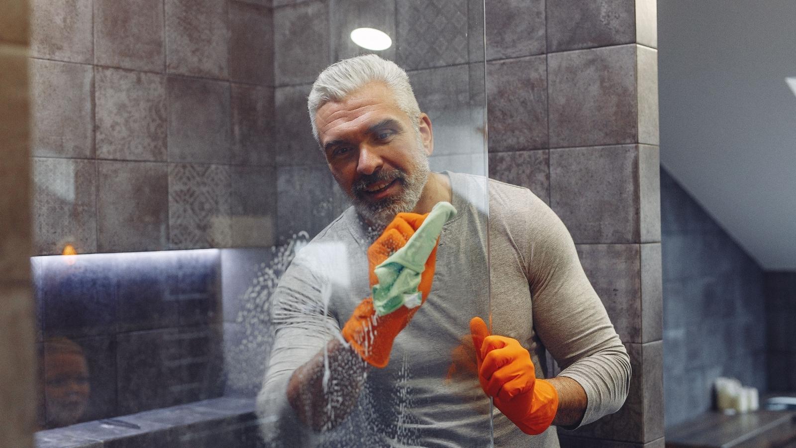 Man Asks His Six Roommates To Share The Cleaning, But They Refuse And Leave Him Doing It All Man cleaning a shower in shared home