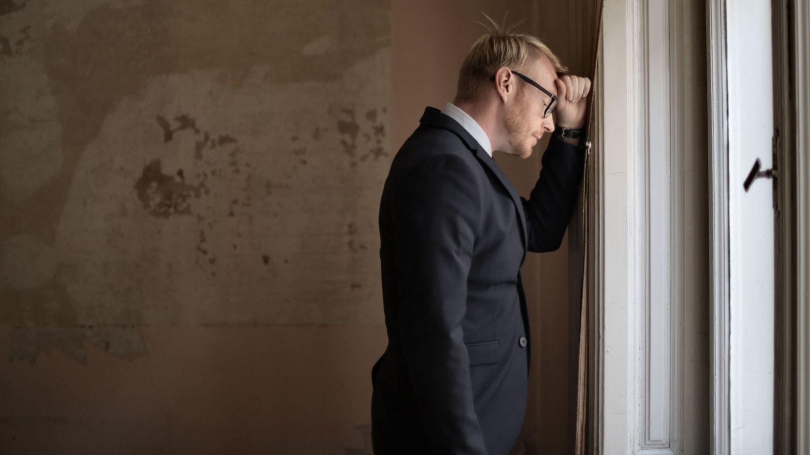 Man stressed with his head against the wall