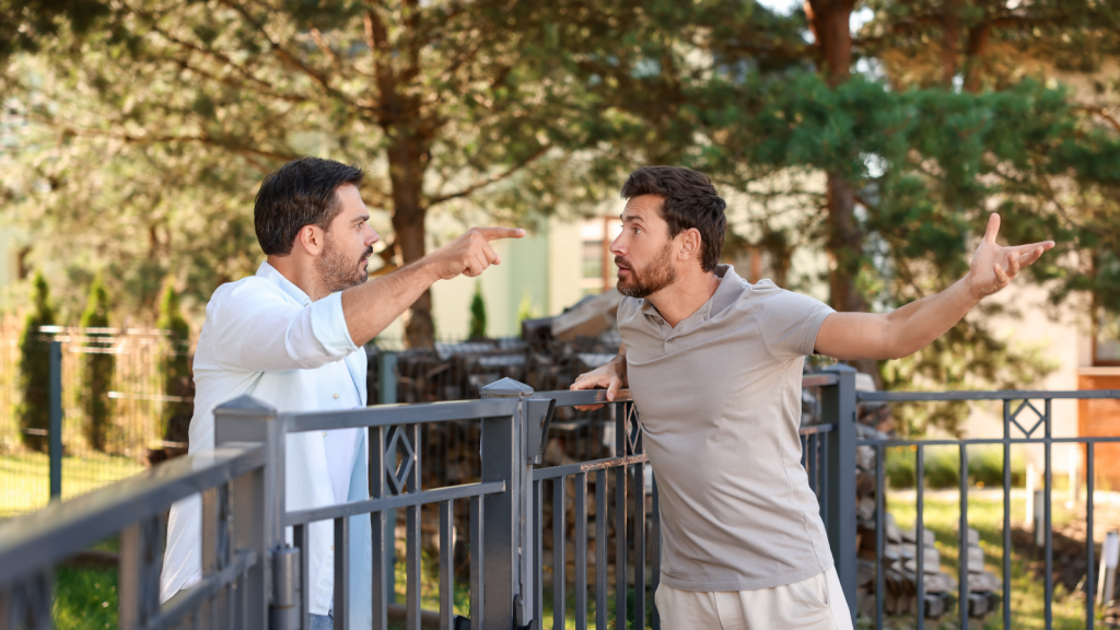 two men arguing across a fence