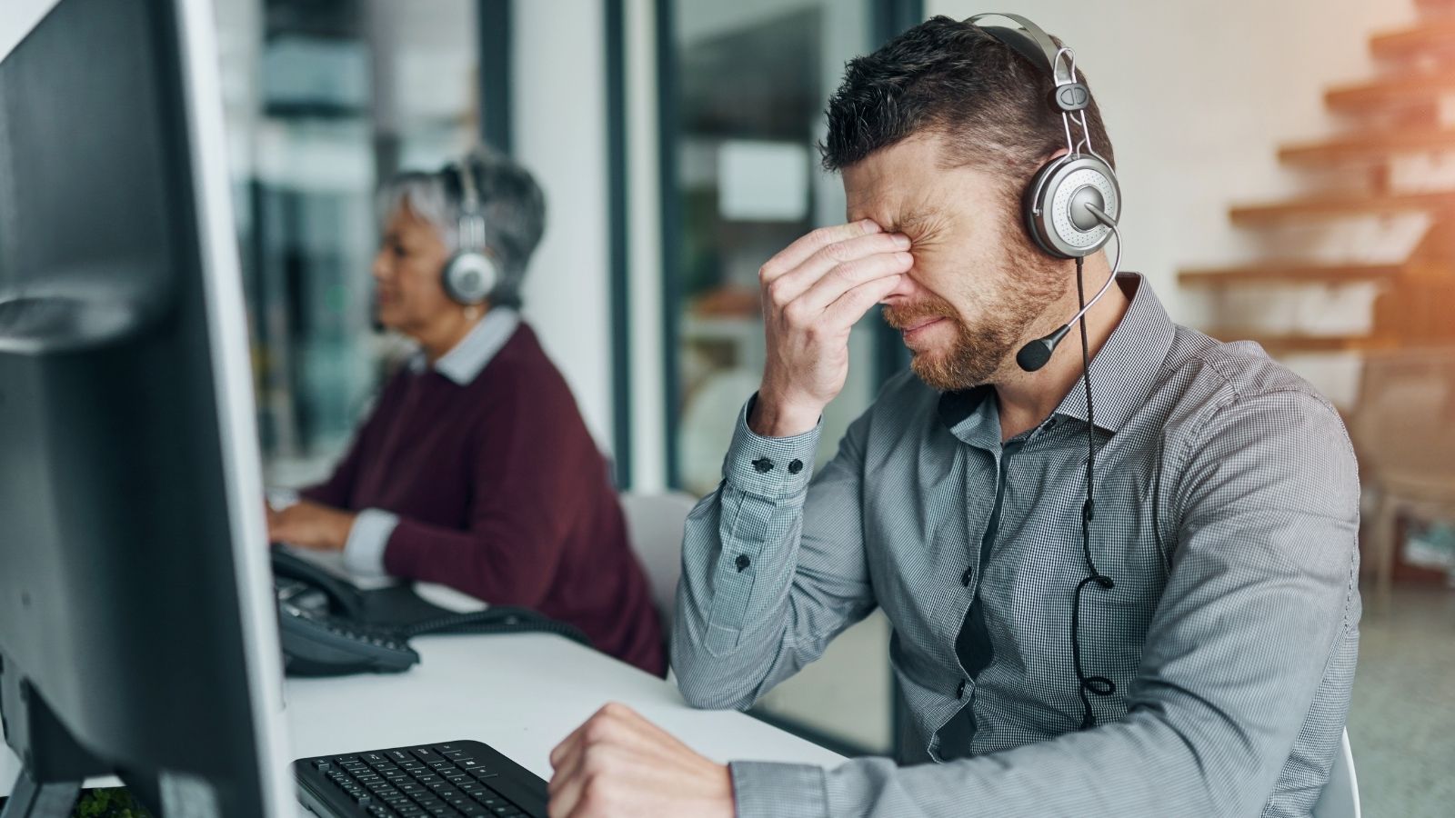 Tech Support Worker Is Really Frustrated With A Lot Of Callers, But He Tries To Stay Polite So He Doesnt Lose His Job frustrated man working in a call center
