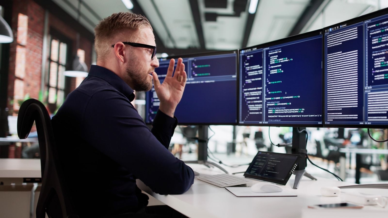 He Was Tasked With Building A New Ticketing System — But He Cant Create Reports Until Departments Tell Him What They Need frustrated man looking at multiple computer monitors full of code
