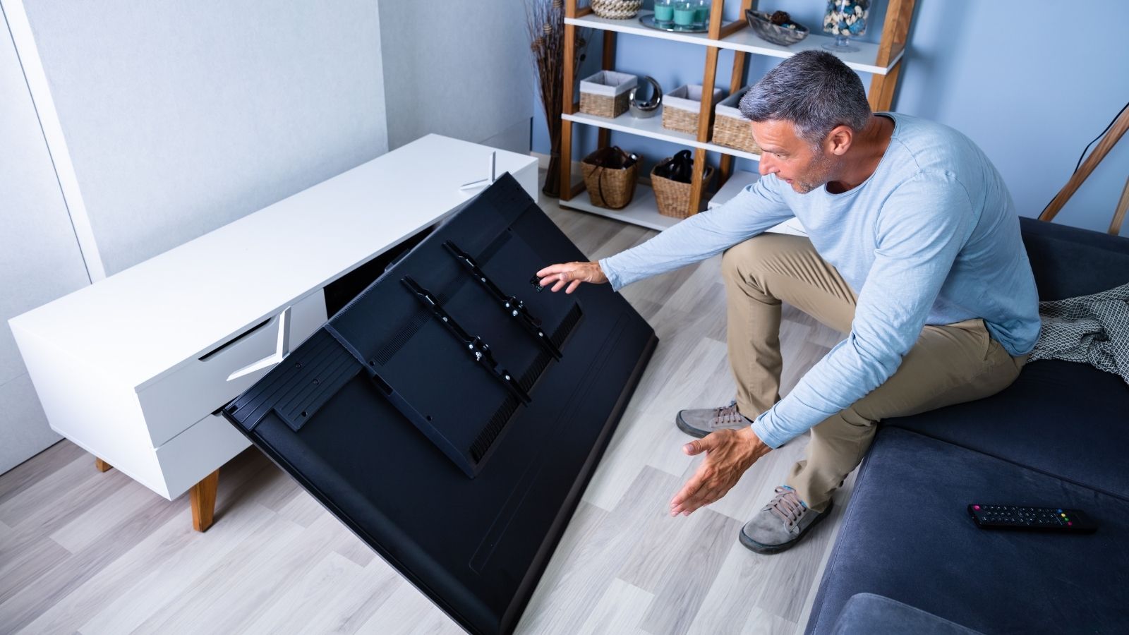 man sitting in front of a broken TV