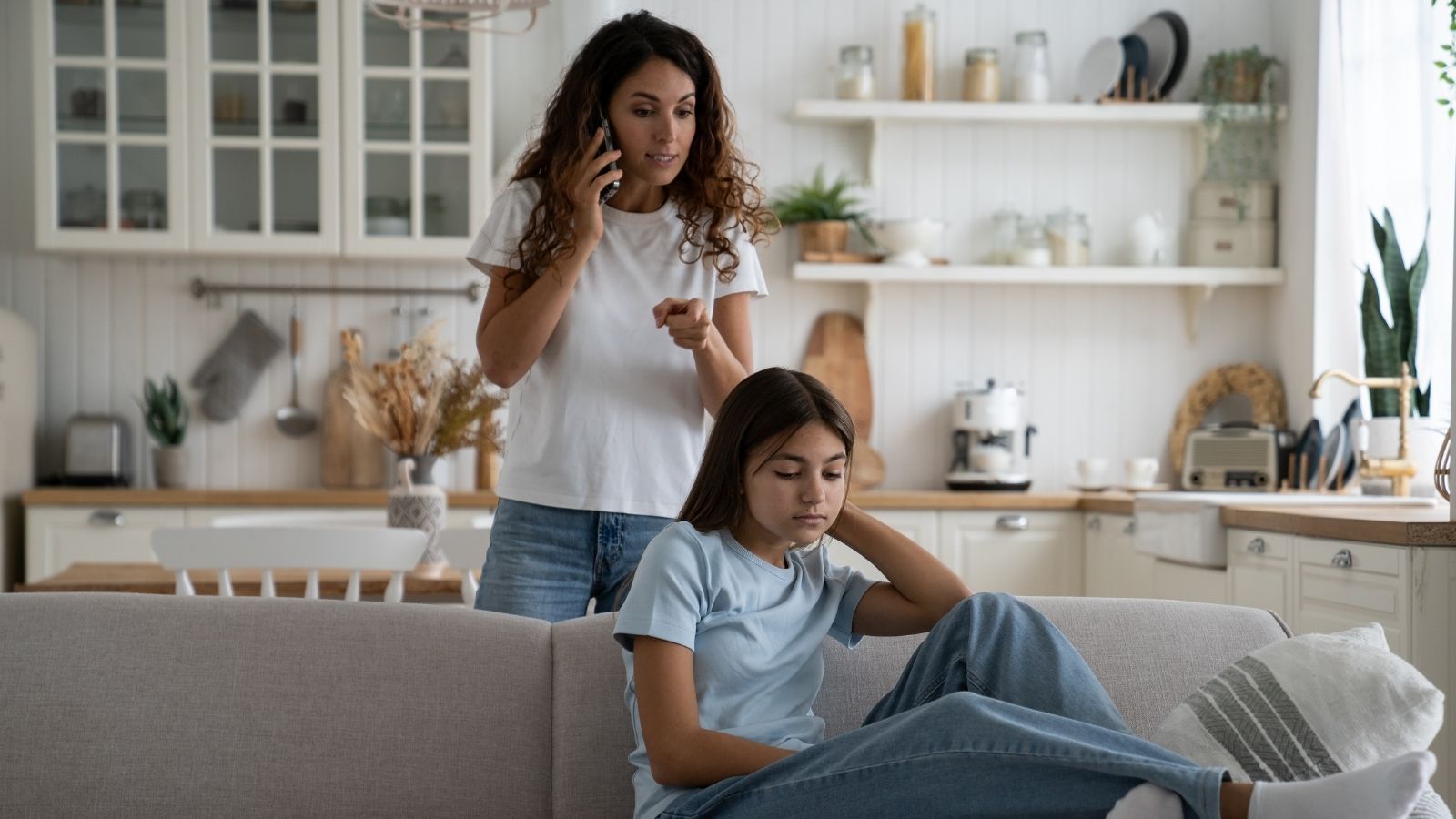 mom talking on the phone while her daughter sits on the couch