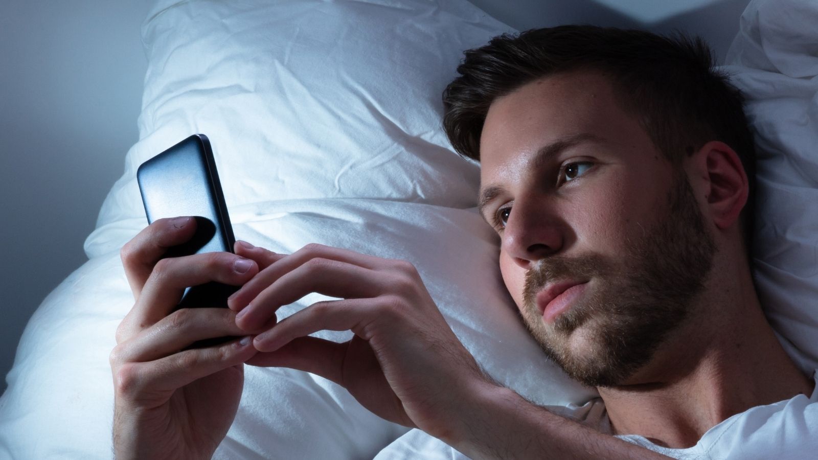He Was Excited for His Dad to Visit — Then His Dad Left After Sending Just a Few Texts man looking at his phone in bed