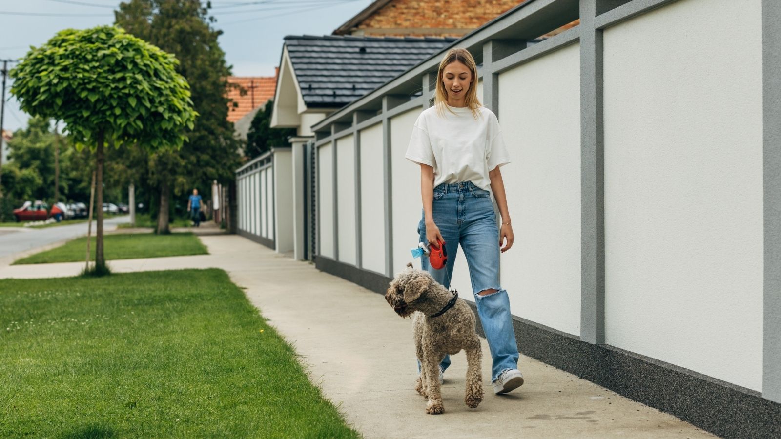 Her Neighbor Stares at Her Every Time She Walks Her Dog — She Refuses to Change Her Route Because of Him young woman walking dog in neighborhood
