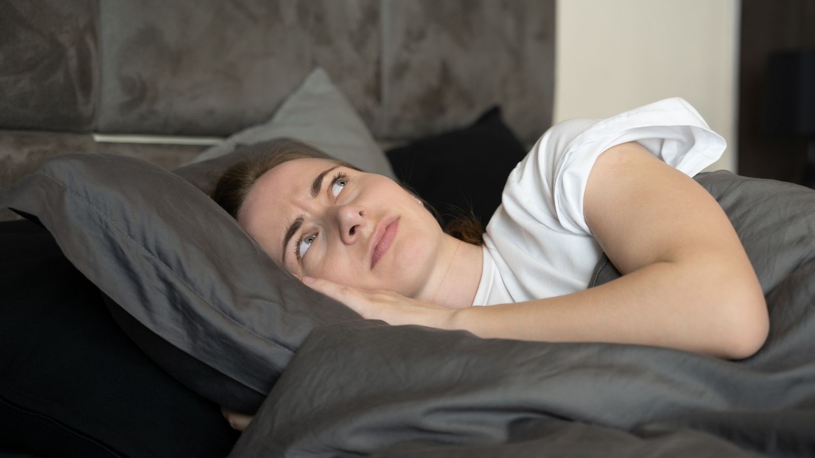 Her Upstairs Neighbor Wont Stop Being Loud At Night — And The HOA Wont Do Anything About It woman having trouble sleeping because of noisy upstairs neighbors