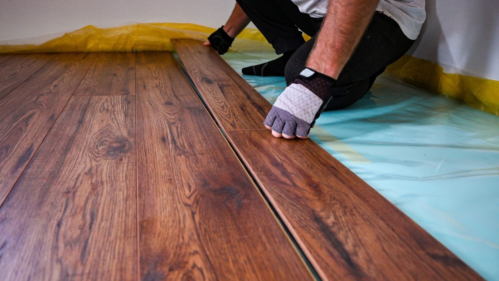 They Spent $12,000 Upgrading Their Condo to Hardwood—Then the HOA Demanded They Rip It Out and Install Wall to Wall Carpet construction worker installing hardwood floors