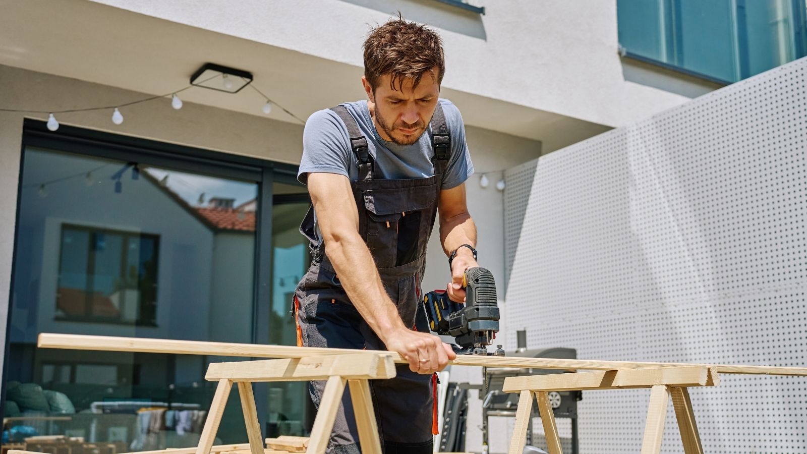 Their Neighbors Are Always Mid Construction Project, And The Couple Is Desperate For The Noise To Finally Stop man sawing a wooden board in his backyard