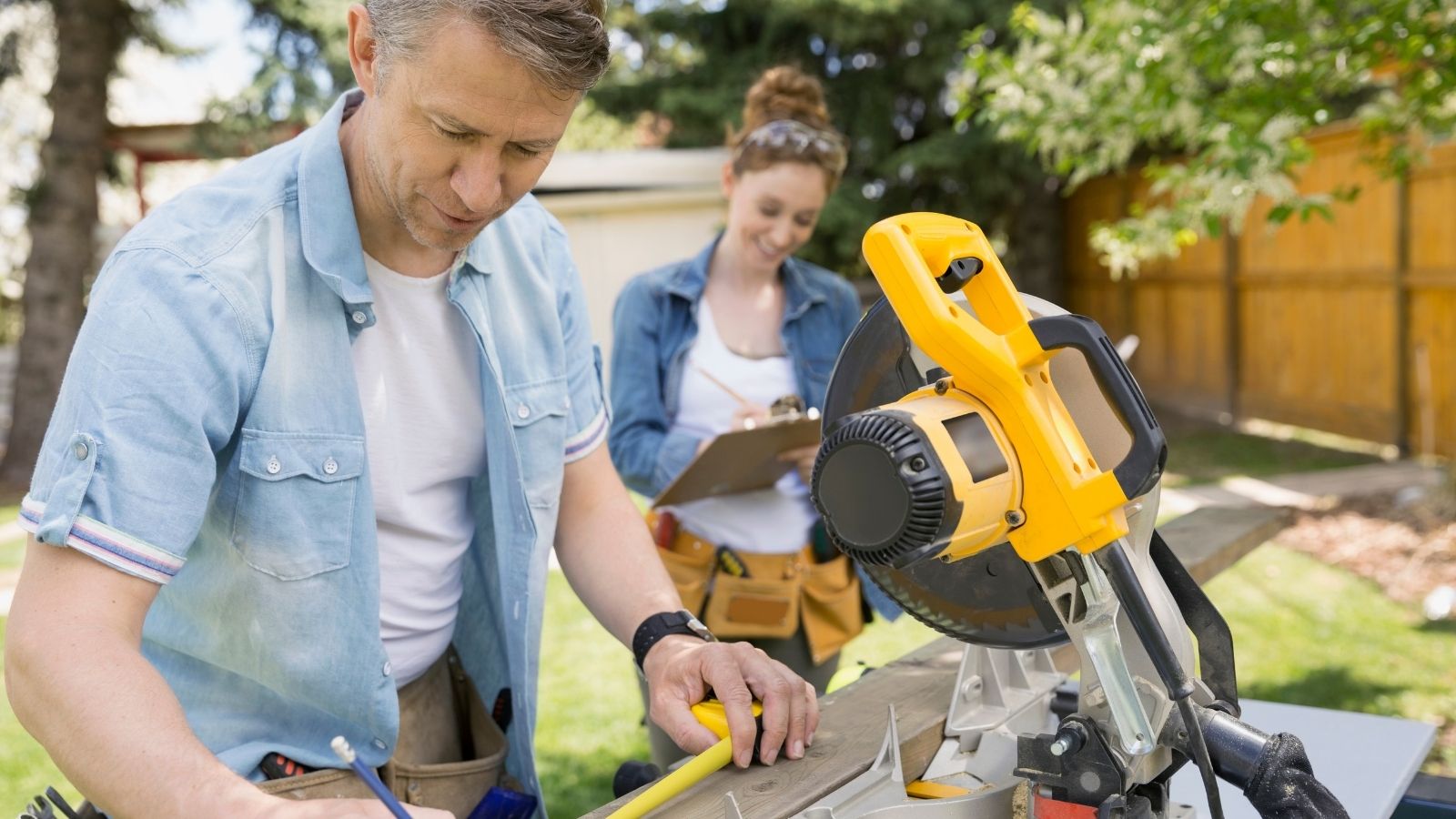 couple using a table saw in their backyard