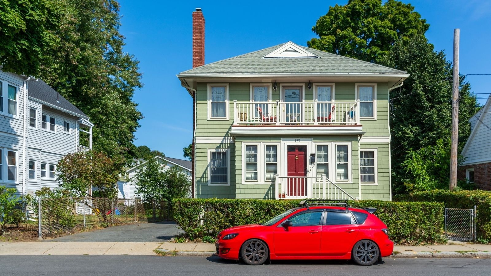A Neighbor Keeps Complaining About Them Parking In Front Of Her House, Even Though She Doesnt Own The Spot red car parked in front of a green house