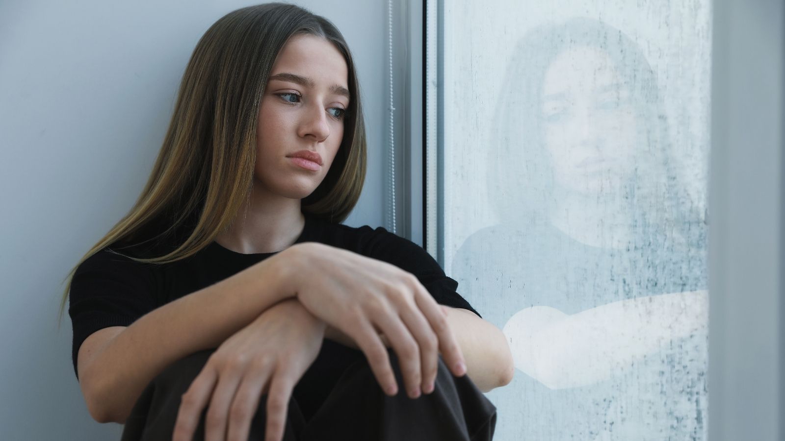 sad teenage girl looking out the window