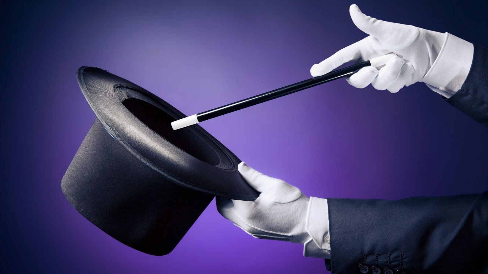 closeup of a magician holding a magic wand and a top hat