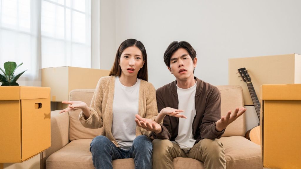 unhappy couple sitting on a couch next to moving boxes