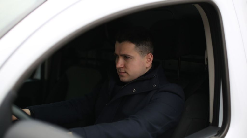 man sitting in the driver's seat of a white vehicle