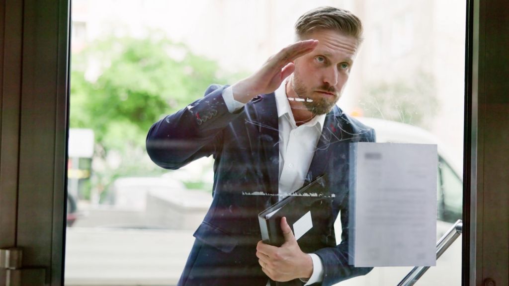 man in a suit looking through a glass door