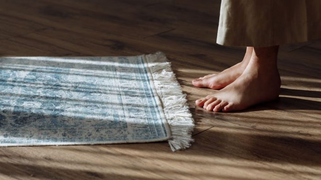 Woman with bare foot stepping on a wooden floor