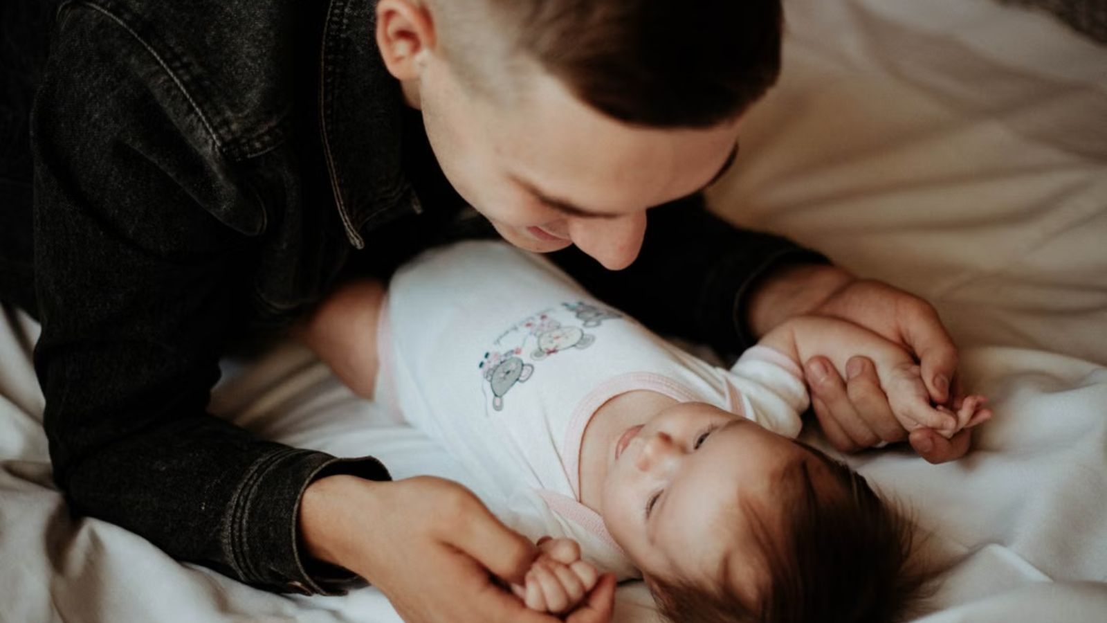 A New Mom Begged Her Family Not to Kiss Her 10 Week Old Baby—Then Her Brother in Law Deliberately Did It While Sick With a Cold Man holding the baby really closely while on bed