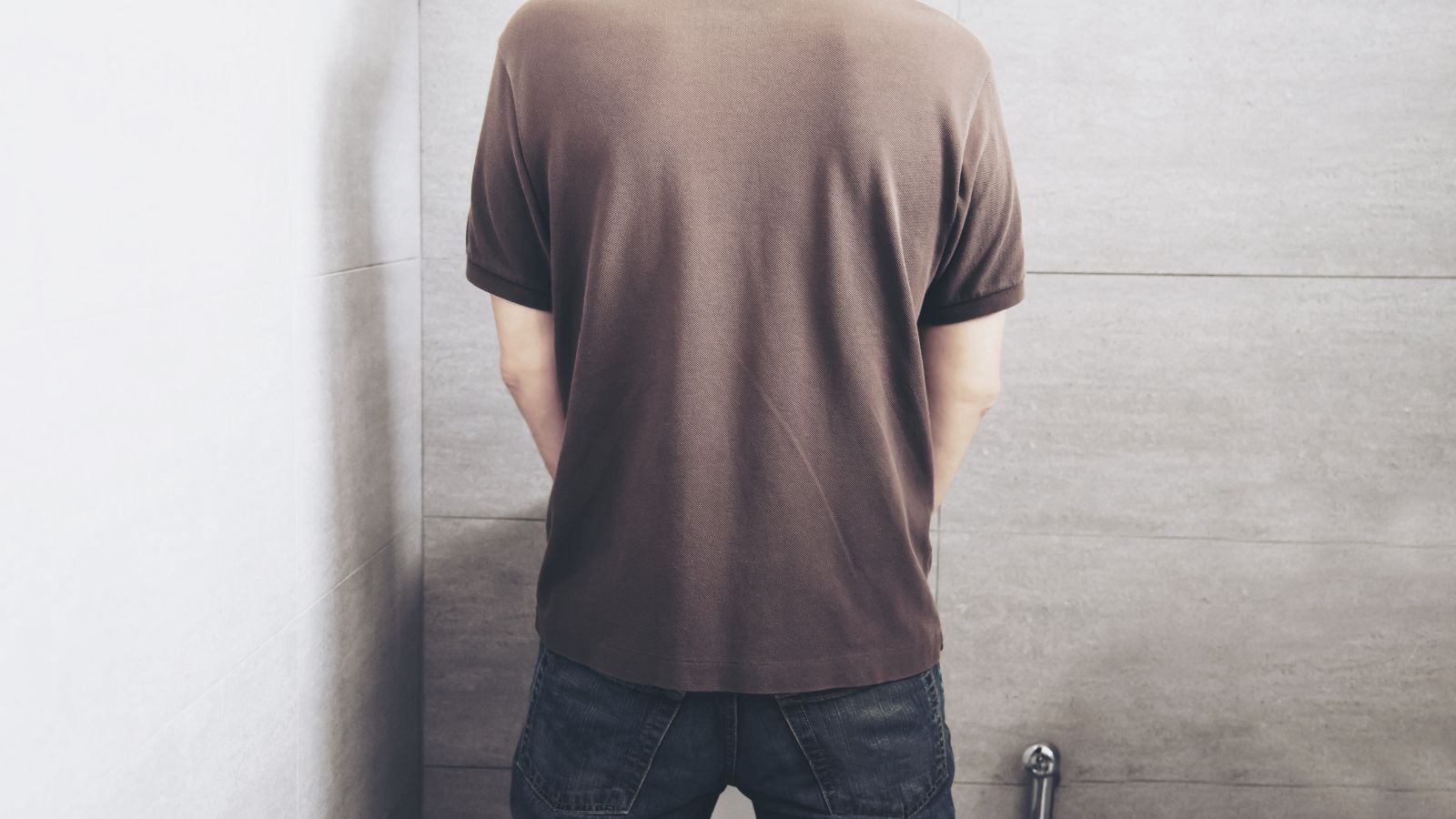Man Rushed Home From Work Straight to the Bathroom—But His Partner Was Upset He Didn’t Give Her a Two Second Hug First Man standing up and using the toilet