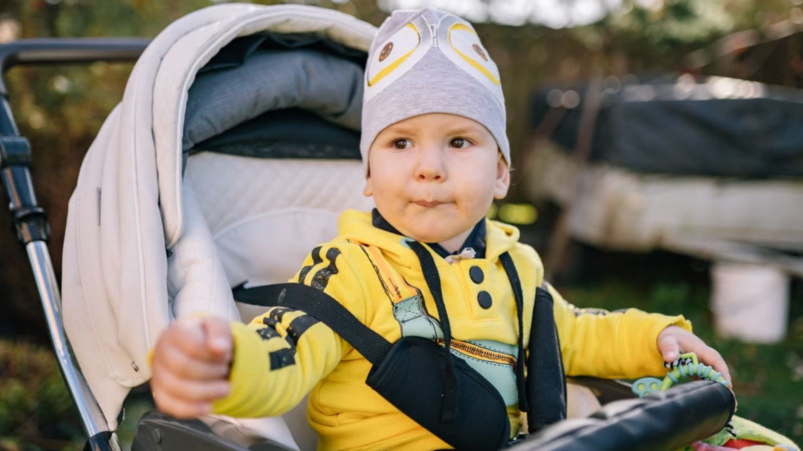 Employee Found a Child Sleeping Alone at an Italian Museum—Then the Parents Said Leaving Her Unattended Was Completely Normal Baby wearing beanie and yellow jacket sitting on a stroller