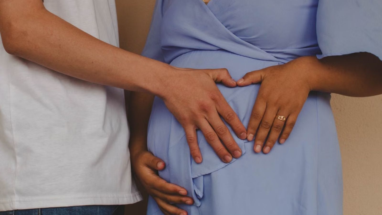 They Planned to Bring Their 4 Month Old to a Destination Wedding—Now His Sister in Law Claims It’s an Insult to Her Big Day Man and woman touching the baby bump