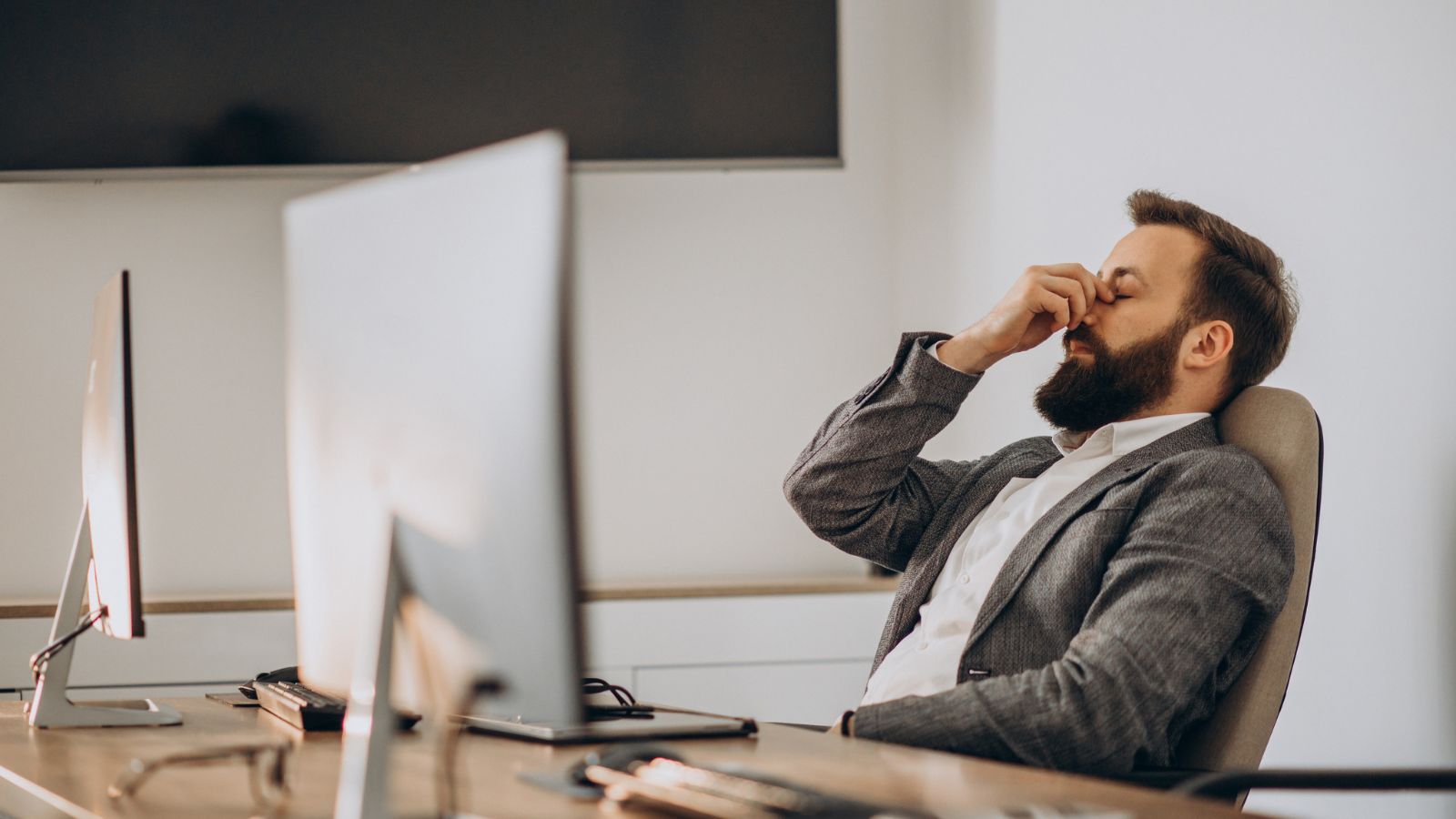 Man in business suit feeling tired in the office