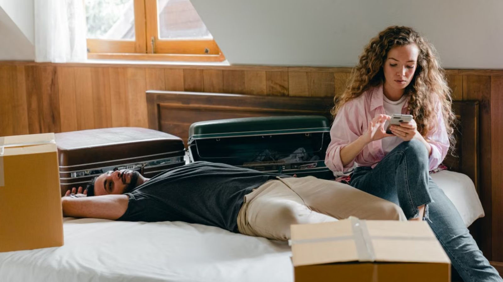 Man and woman on the bed surrounded by boxes and suitcases