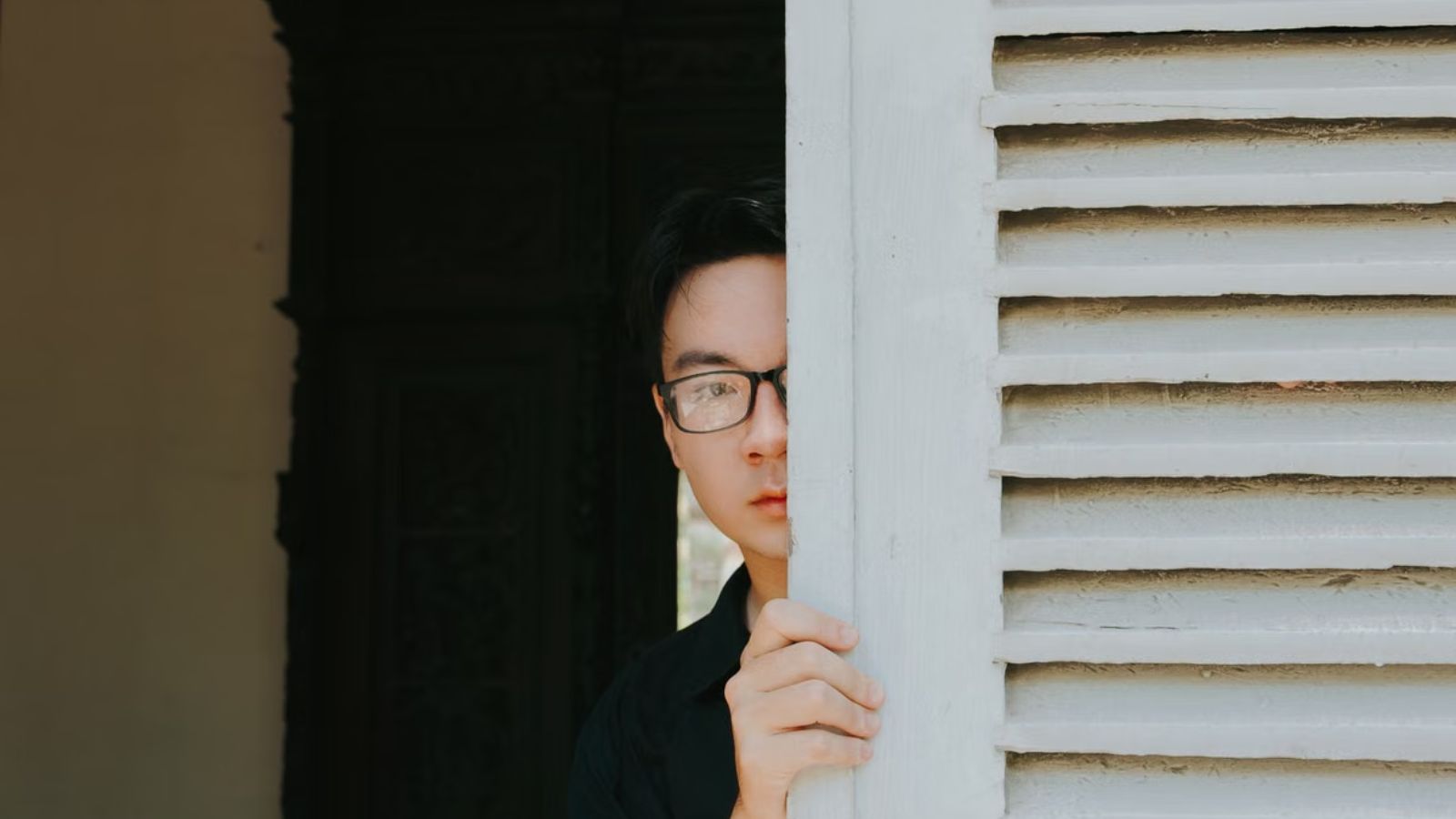 Her Neighbors Kept Trespassing on Her Property—So She Frosted Her Windows to Stop Them From Peeking In Man peeking from behind a louvered door indoors