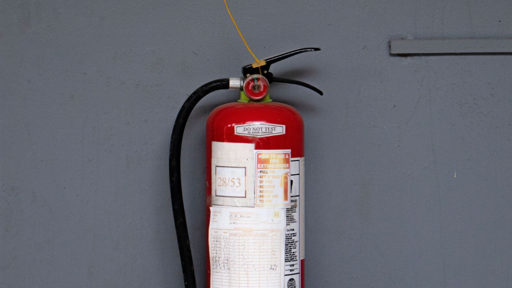 A fire extinguisher placed against a gray wall
