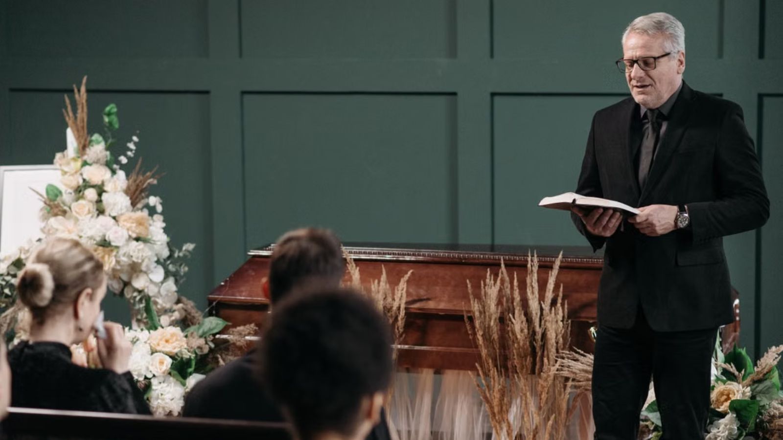 Woman Learned Her Estranged Stepfather Had Died, But She Decided Not To Attend His Funeral A funeral service with a priest holding the bible and talking in front