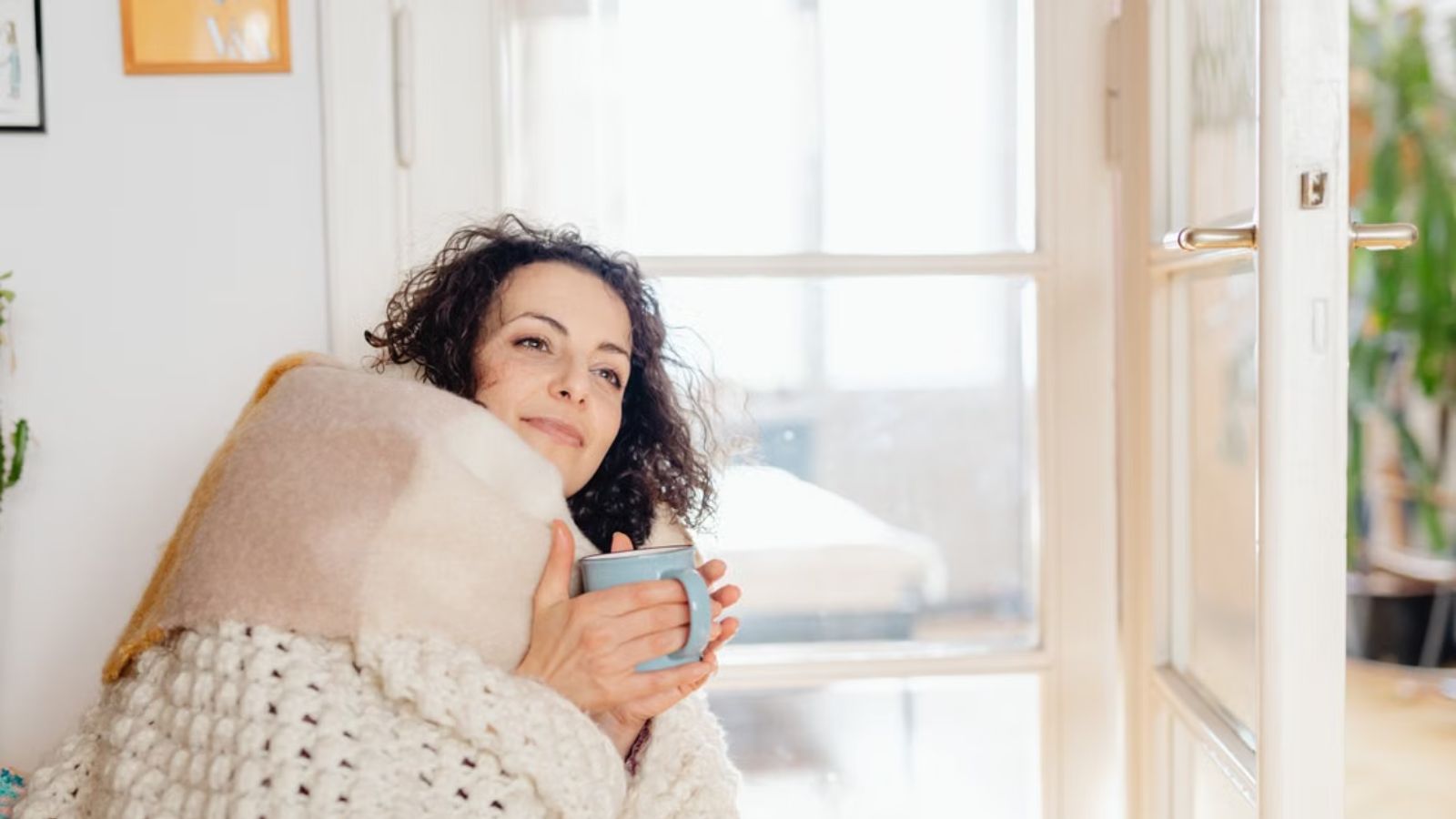 She Documented 3:00 AM Noise Spikes and Ordinance Violations—Then Her College Neighbor Turned Into a Respectful Tenant Woman holding a mug while being wrapped by a thick blanket at home