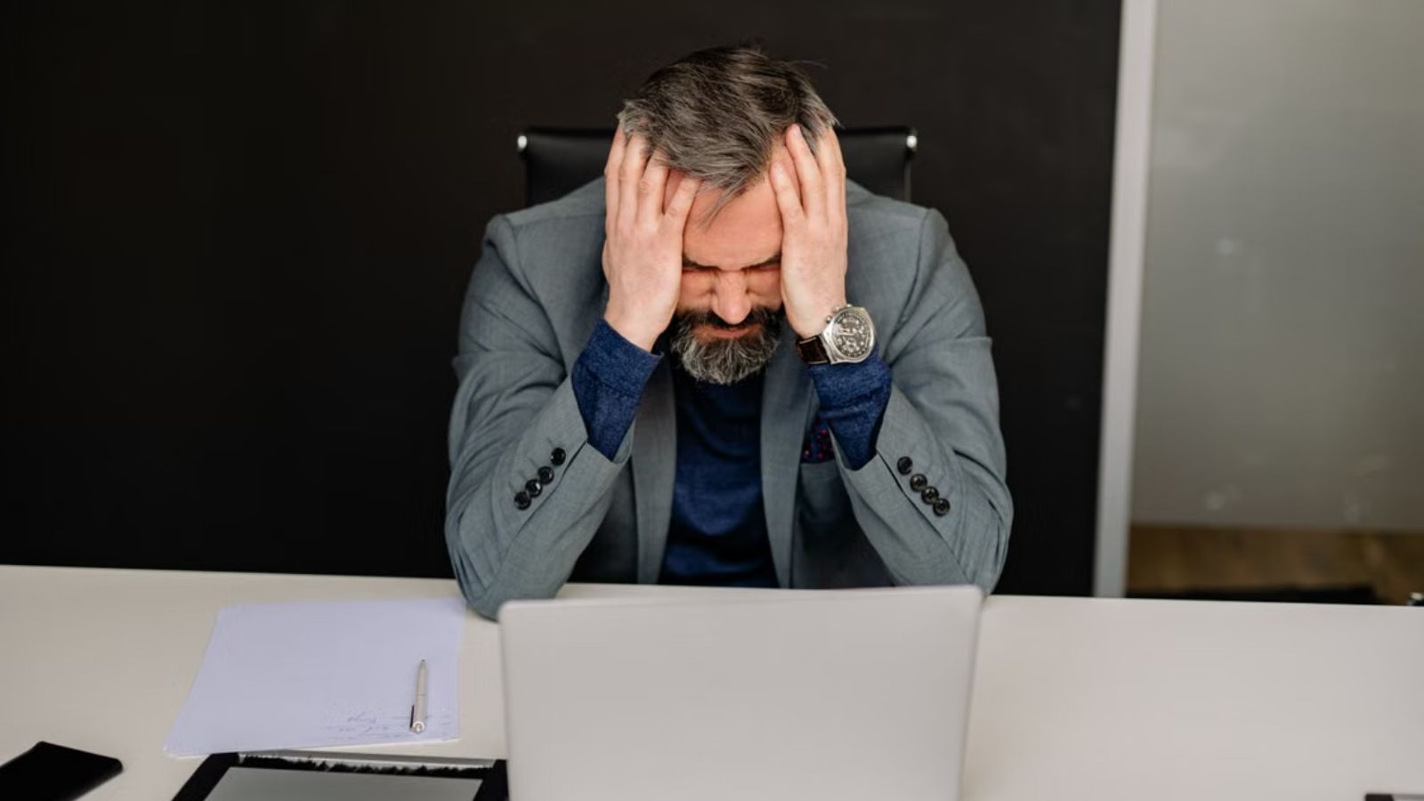 Employee Was Told To Trust Sales And Stop Reviewing Small Contracts, But One Small Contract Became A Huge Problem Man in business attire touching his head in frustration in the office