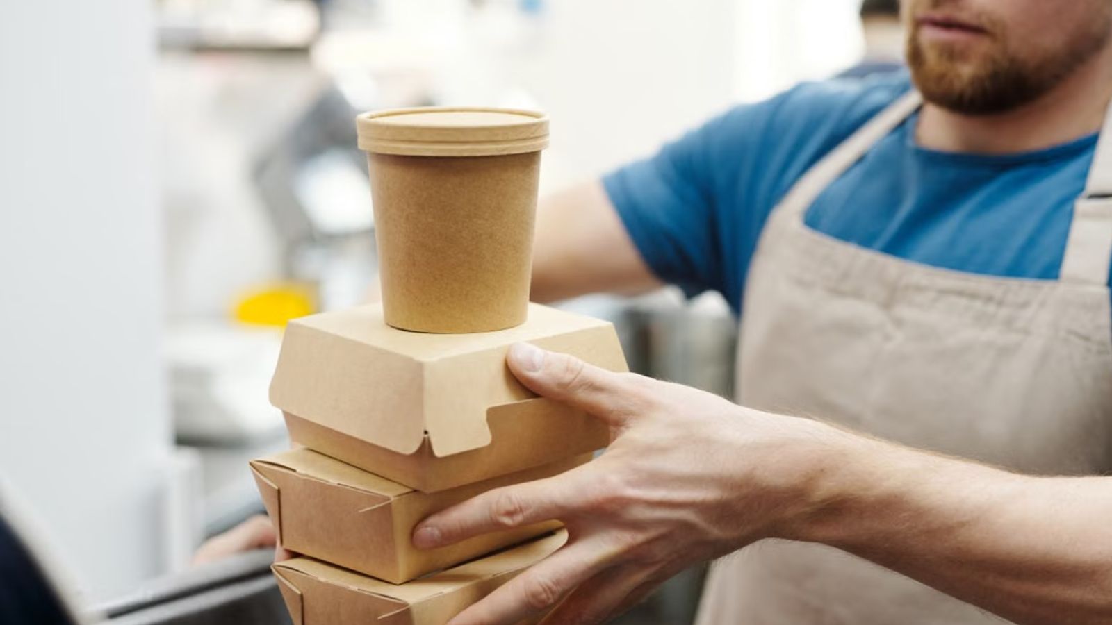 Restaurant staff packing and handing out orders in takeout boxes